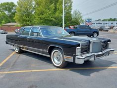 an old black car parked in a parking lot