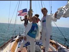 two people standing on the deck of a sailboat