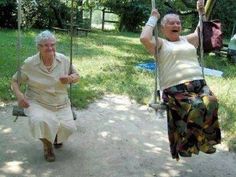 an older woman swinging on a swing with another old lady in the back ground behind her