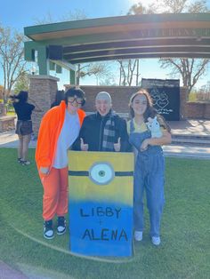 three people standing in front of a sign that says libby the aliena