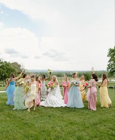 a group of bridesmaids walking in the grass with their arms in the air