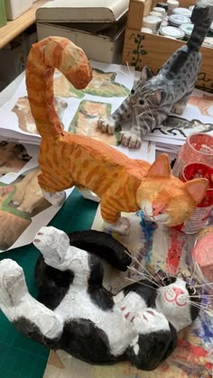 two cats made out of clay sitting next to each other on top of a table