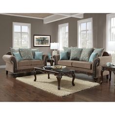 a living room filled with furniture and pillows on top of a wooden floor next to windows