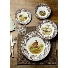 three plates with birds painted on them sitting on a place mat next to silverware