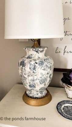 a blue and white vase sitting on top of a table next to a lampshade