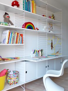 a room with white shelves filled with books and toys