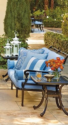 a blue couch sitting on top of a patio next to a table filled with flowers