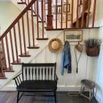 a black bench sitting under a stair case next to a wooden bannister on the wall