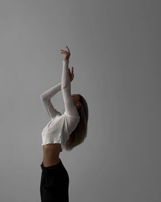 a woman in white top and black skirt doing yoga exercises with her hands up to the side