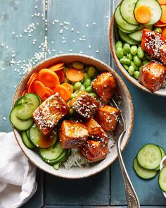 two bowls filled with meat and vegetables on top of a blue table next to each other