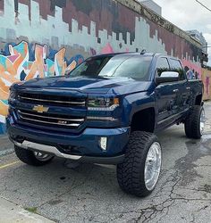 a blue truck parked in front of a graffiti covered wall