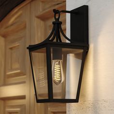 an outdoor light hanging on the side of a building with a door in the background