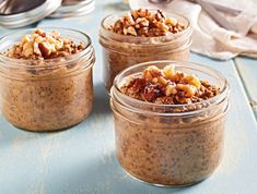 three jars filled with granola sitting on top of a blue table