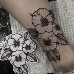 a black and white flower tattoo on the right leg, with two smaller flowers behind it