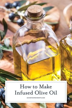 two bottles of olive oil on a wooden table with blueberries and leaves in the background