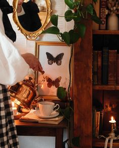 a woman pouring tea into a cup on top of a table next to a mirror