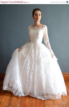 a woman in a white dress standing on a wooden floor