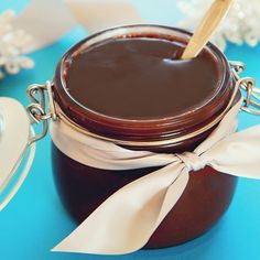 a jar filled with chocolate sitting on top of a blue table next to white napkins