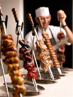 a chef is preparing skewers of meats and sausages