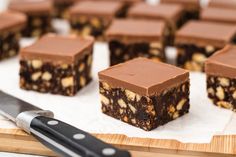 there are many pieces of brownies on the cutting board with a knife next to it