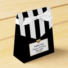 a black and white striped gift bag with a gold heart on the tag that says thank you