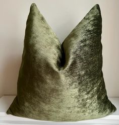 a green pillow sitting on top of a white shelf