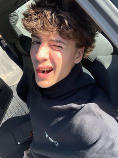 a young boy sitting in the back seat of a car with his tongue hanging out