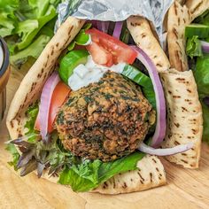 a burger with lettuce, tomato and onion on it next to some pita bread