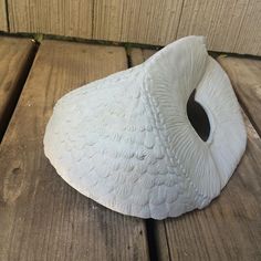 a white bird statue sitting on top of a wooden table next to a brick wall