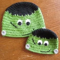 two crocheted hats sitting on top of a wooden table