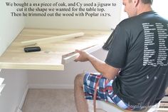 a man sitting at a desk working on some wood