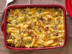 a red casserole dish filled with pasta and broccoli on a table