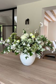 a vase filled with white flowers on top of a wooden table