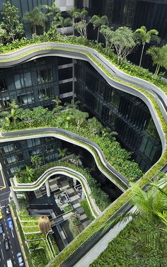 an aerial view of a building with green vegetation growing on the side of it and cars driving down the street