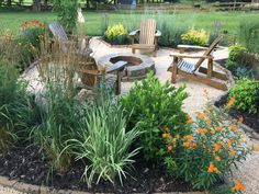 an outdoor fire pit surrounded by flowers and chairs in the middle of a garden area