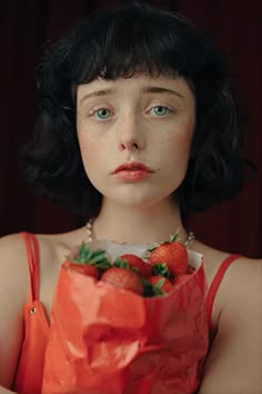 a woman holding a bag full of strawberries