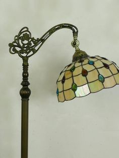 a floor lamp with a stained glass shade on the top and bottom of it's arm