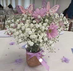 a vase filled with lots of white and pink flowers on top of a table covered in confetti