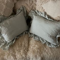 two pillows on top of a bed with ruffled edges