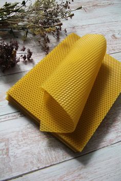 two yellow napkins sitting on top of each other next to dried plants and flowers