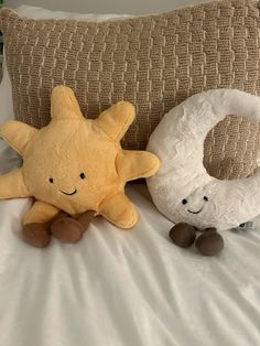 two stuffed animals sitting on top of a bed next to pillows and pillowcases