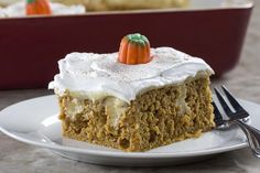 a piece of cake with frosting and carrots on top sits on a plate