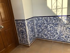 an empty room with blue and white tiles on the wall, door and window sill