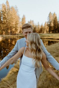 a bride and groom holding hands in front of a lake