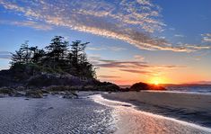 the sun is setting over an island in the ocean with sand and trees on it