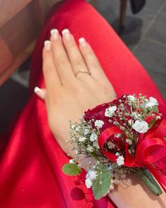 a woman wearing a red dress with flowers on her wrist