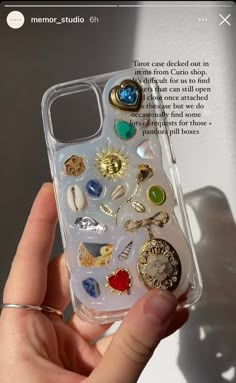 someone is holding up their phone case with many charms on it