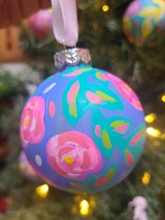 an ornament hanging from a christmas tree decorated with pink and blue flowers on it