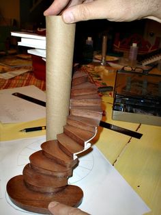 a hand is holding a piece of wood that looks like a spiral staircase