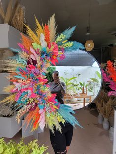 a woman taking a selfie in front of a mirror with colorful feathers on it